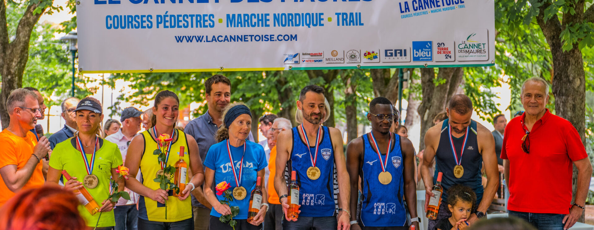 groupe de personnes réunies sur une scène pour une remise de trophées dans un cadre verdoyant