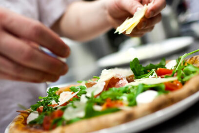 Assiette contenant une pizza, en train d'être préparée par le cuisinier. - Agrandir l'image, fenêtre modale